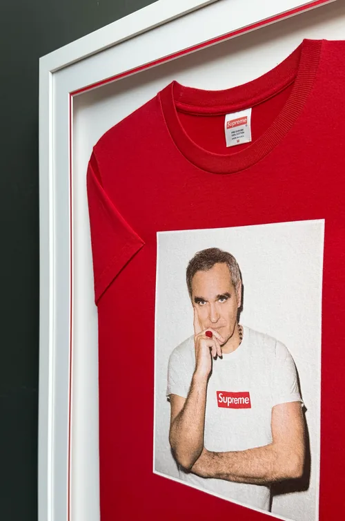 The frame from the side: the Supreme label, the Morrissey photo print and the red line in the mount