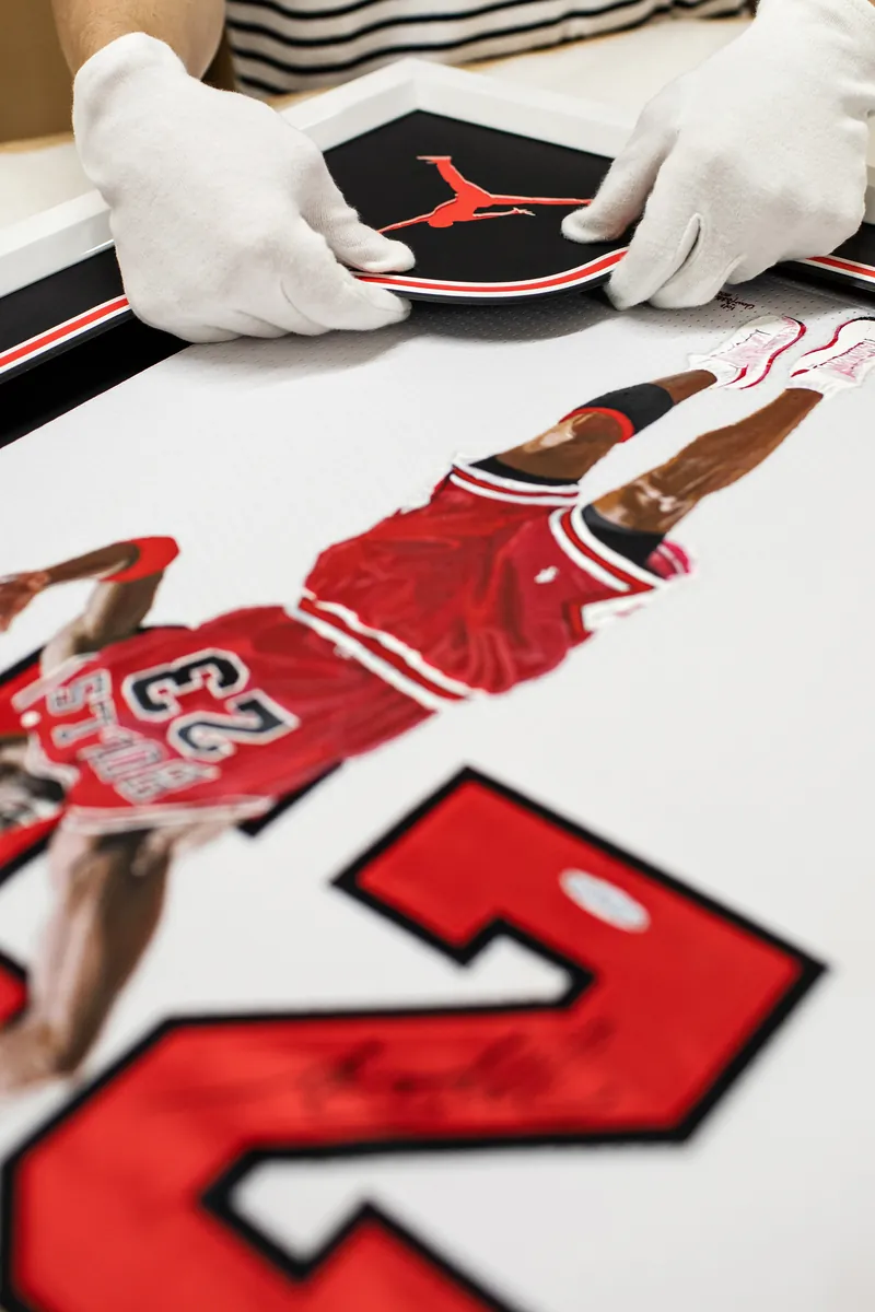 Handling a framed Michael Jordan jersey in white cotton gloves